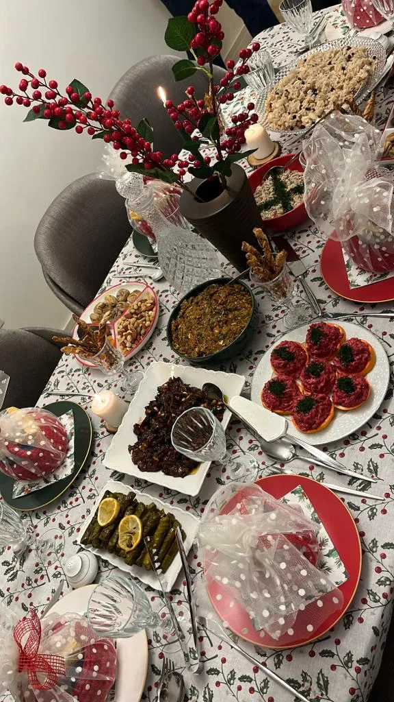 Kırmızı meyveli dallarla süslenmiş sofrada mezeler, sarma, kuruyemiş ve ikramlar